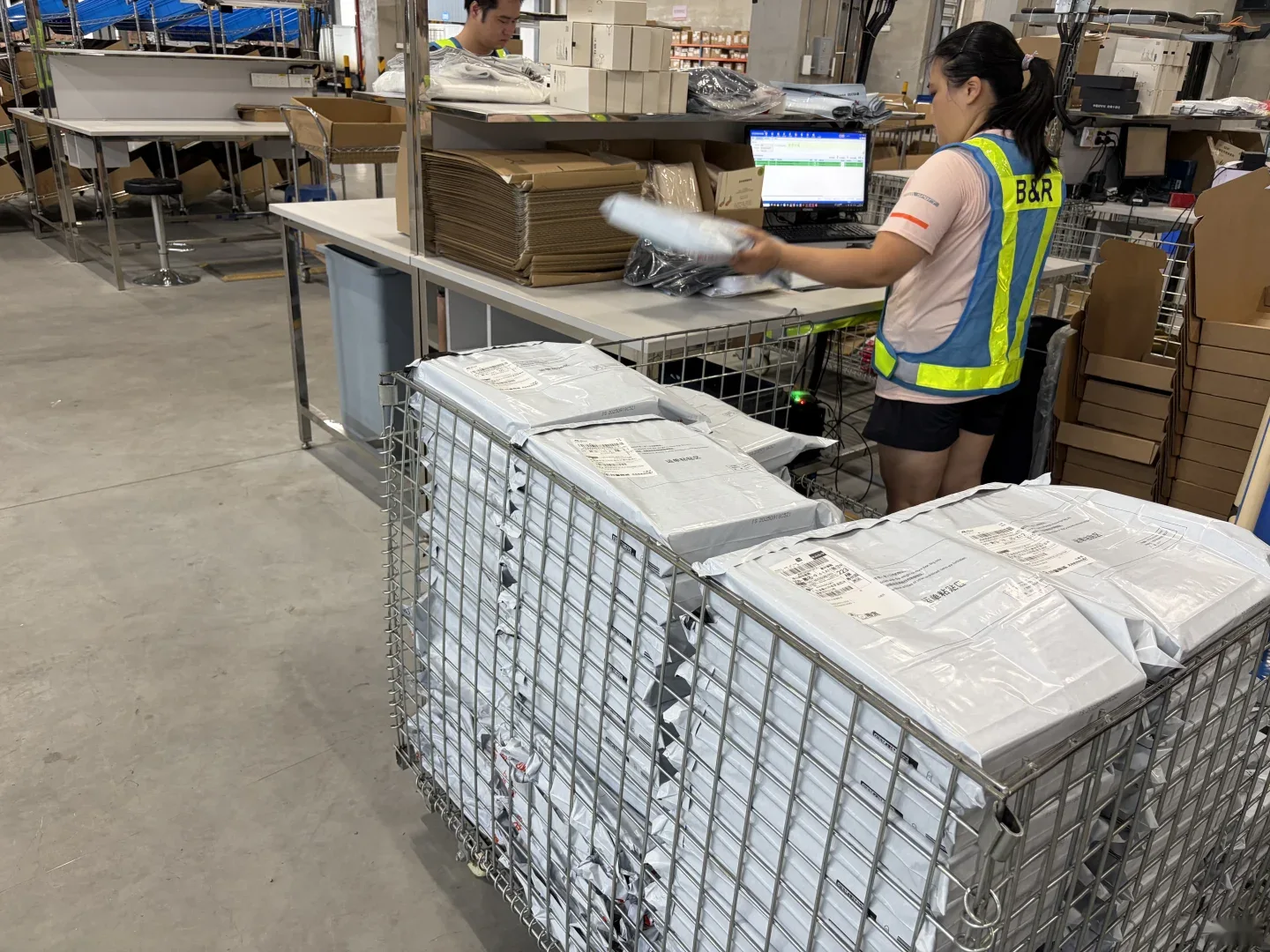 A warehouse operator beside parcel cages and a computer workstation
